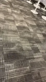 Patterned carpeted floor in an indoor venue with white stanchions along the edge.