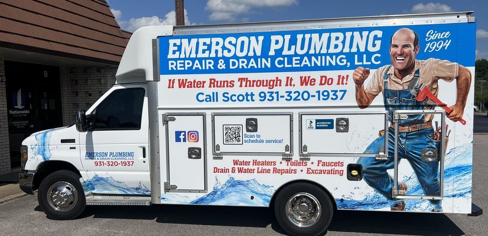 Emerson Plumbing repair van with blue-and-white branding and plumber graphic parked outside a building
