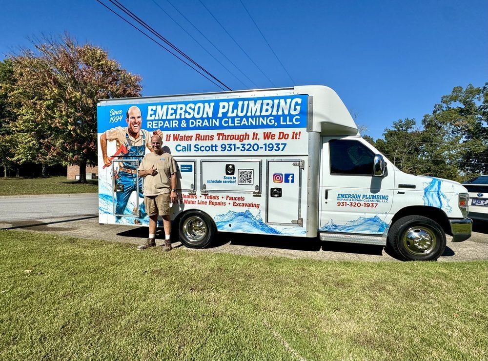 Emerson Plumbing service van parked on grass with a plumber standing beside it.