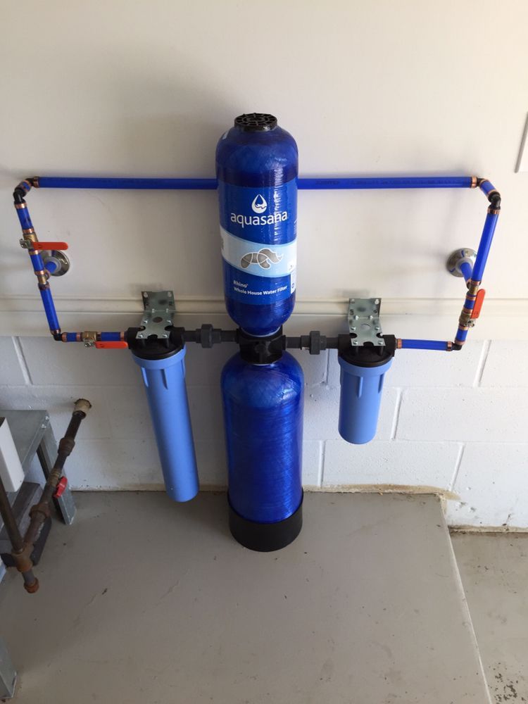 Blue water filtration system with dual filter canisters mounted on a wall.