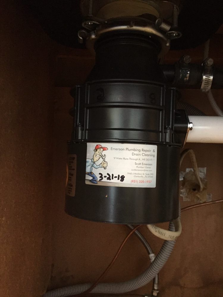 Under-sink garbage disposal with black housing and attached drain pipes