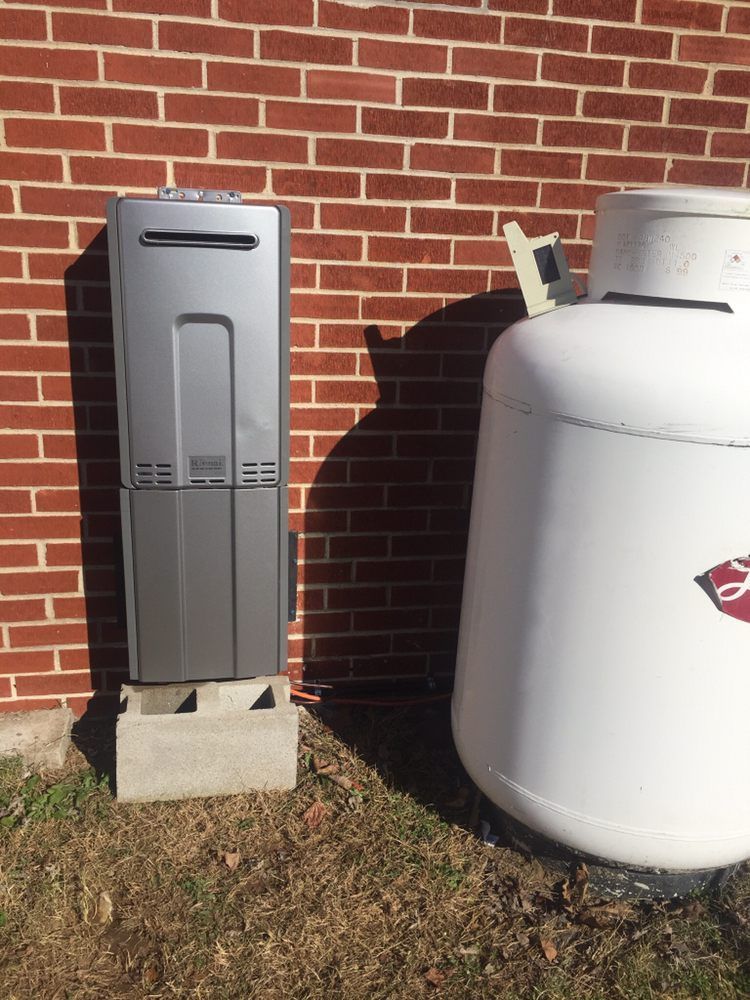 Gray outdoor water cooler beside a white propane tank against a brick wall