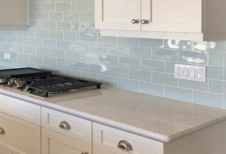Kitchen with light blue subway tile backsplash, white cabinets, and light countertop.