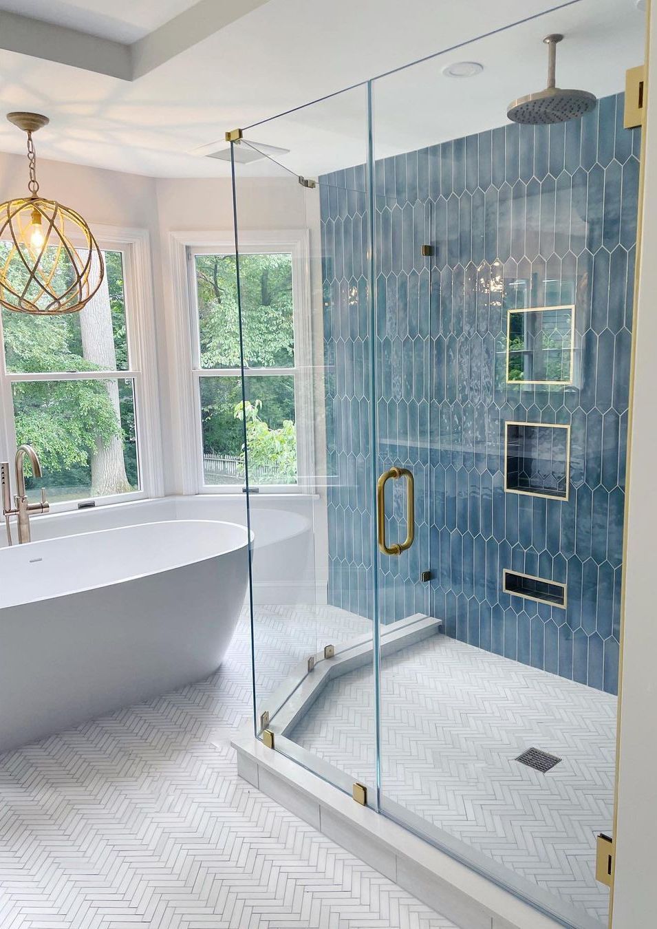 Modern bathroom with blue tile shower, glass enclosure, soaking tub, and large windows.