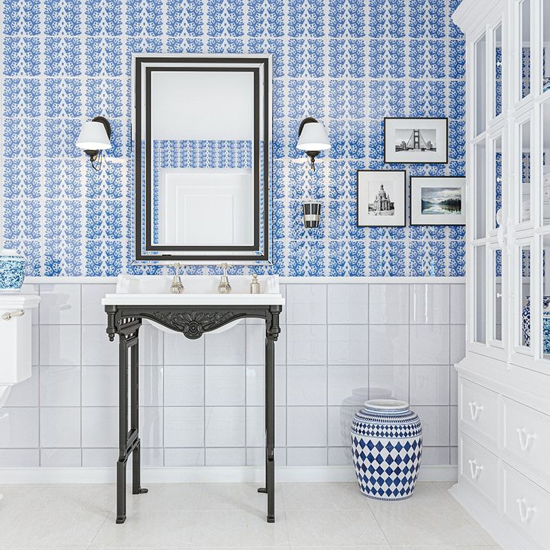 Blue and white bathroom with decorative wallpaper, mirror, sink, and cabinet.