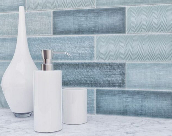 White bathroom decor: vase, soap dispenser, cup, against blue tile wall.