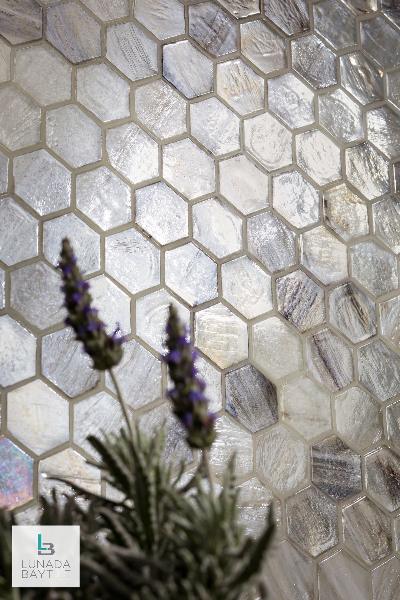Hexagon-tiled wall with a lavender plant in front; tiles are pearlescent and white.
