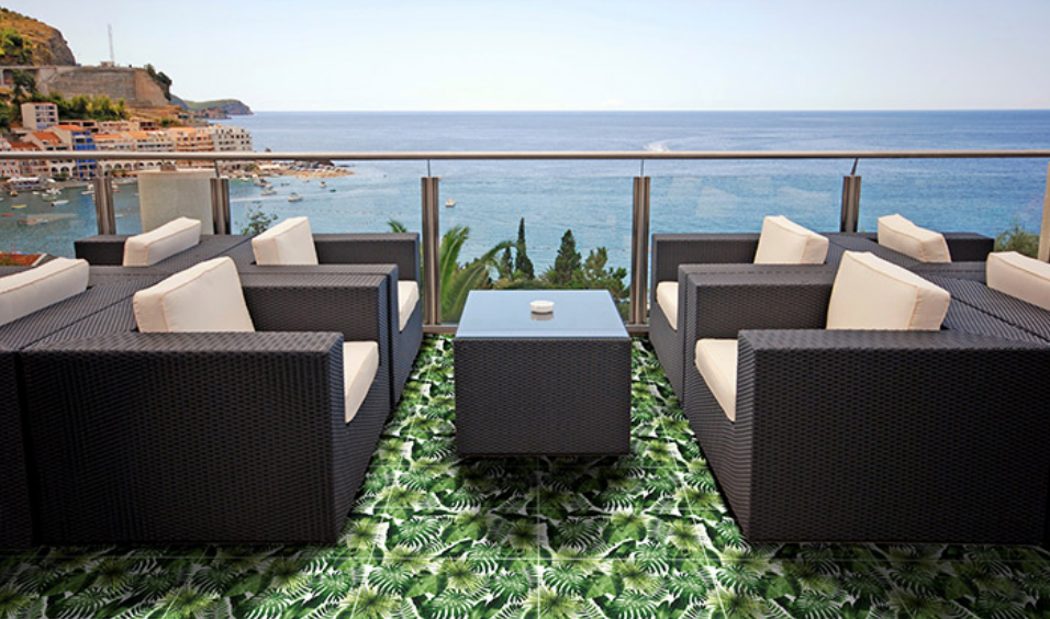 Outdoor lounge area with black wicker furniture, white cushions, ocean view.