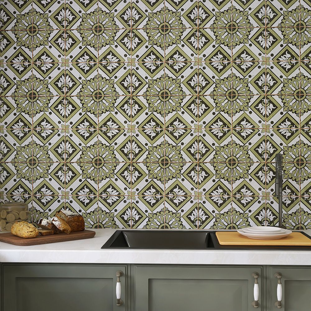 Kitchen backsplash with green patterned tiles above a white countertop and green cabinets.