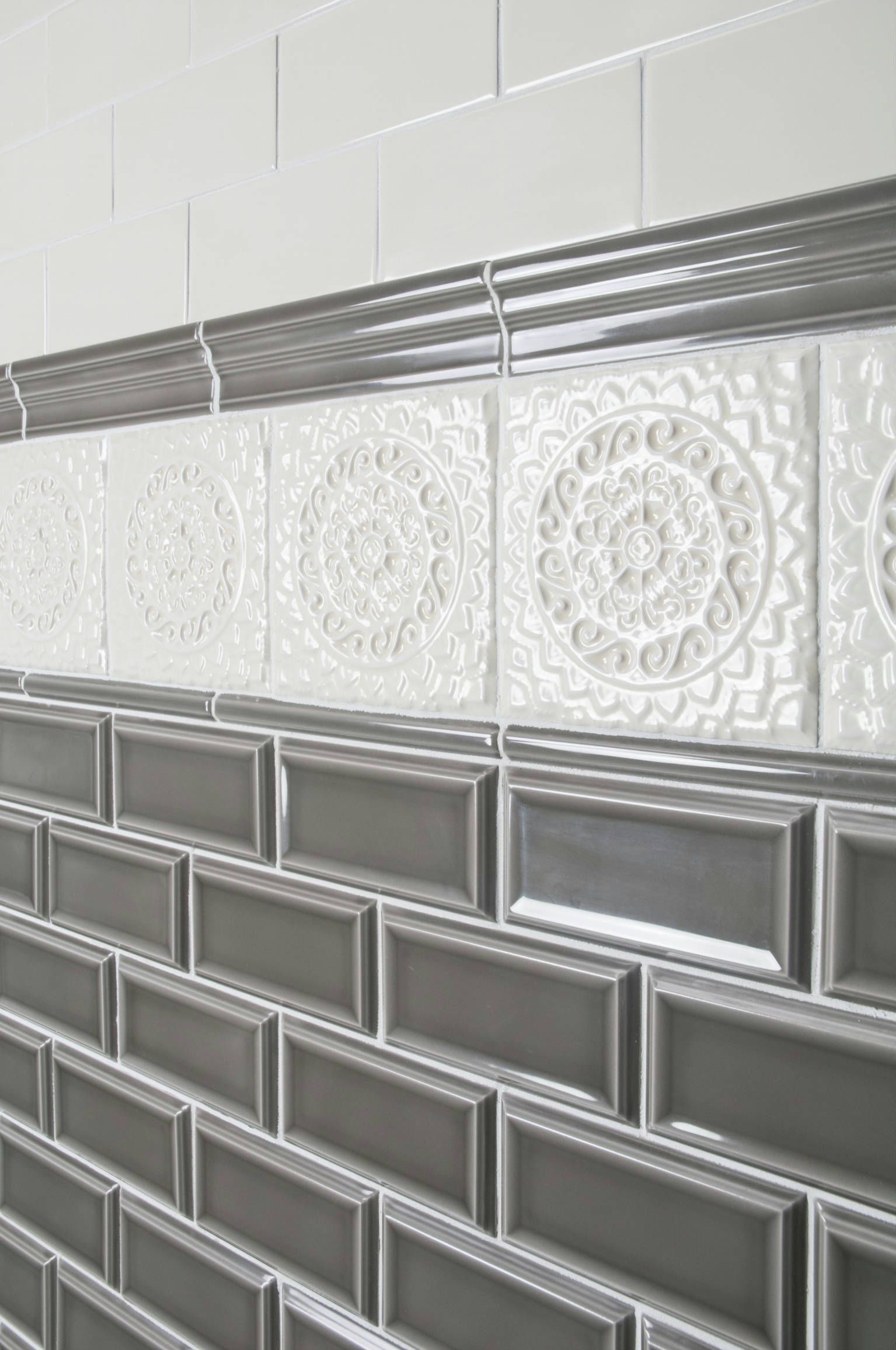 Gray and white tiled wall with decorative medallion tiles.