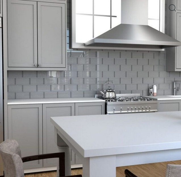 Gray kitchen with cabinets, island, stove, stainless steel hood, and subway tile backsplash.