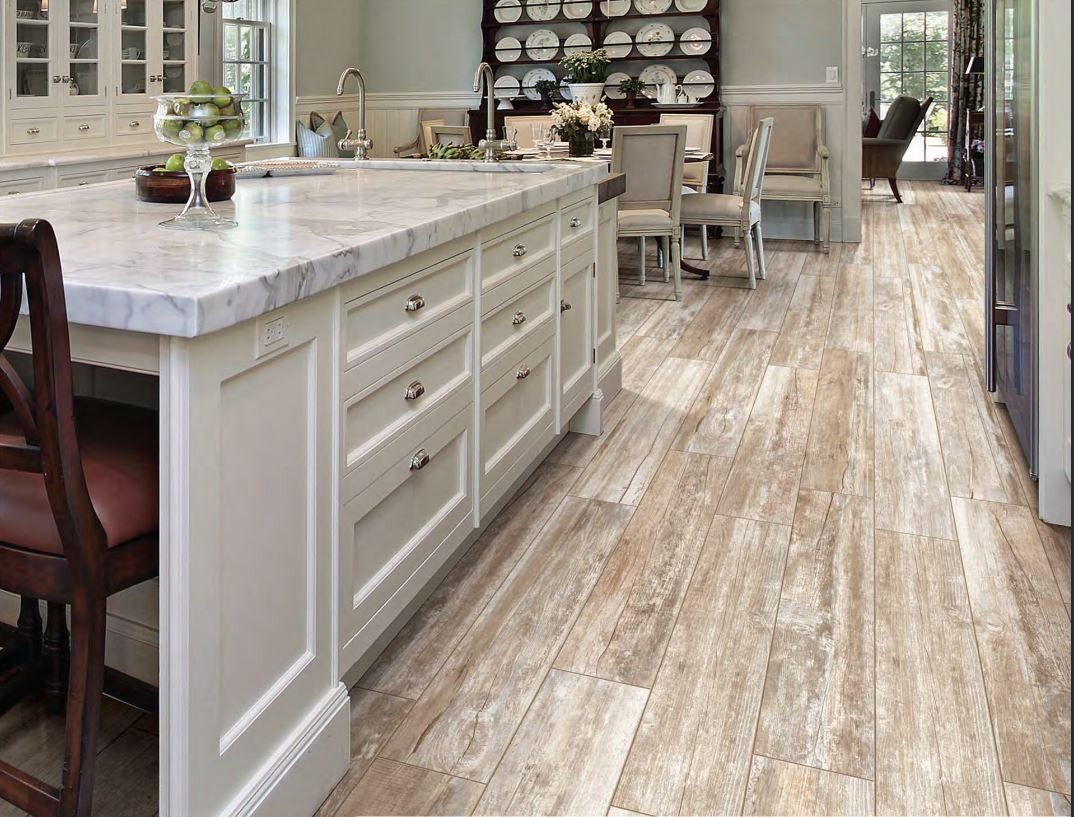Kitchen with beige wood-look floor tiles, white cabinetry, and marble countertop.