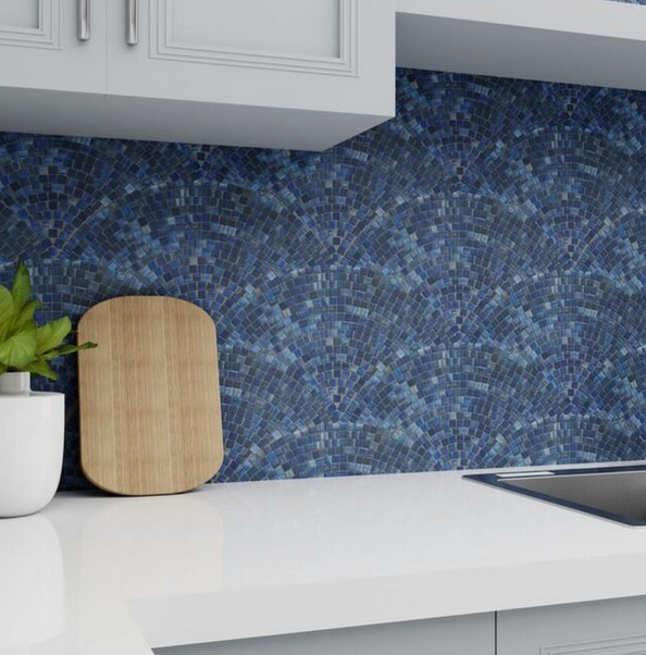 Kitchen counter with blue mosaic backsplash, white cabinets, and a cutting board.