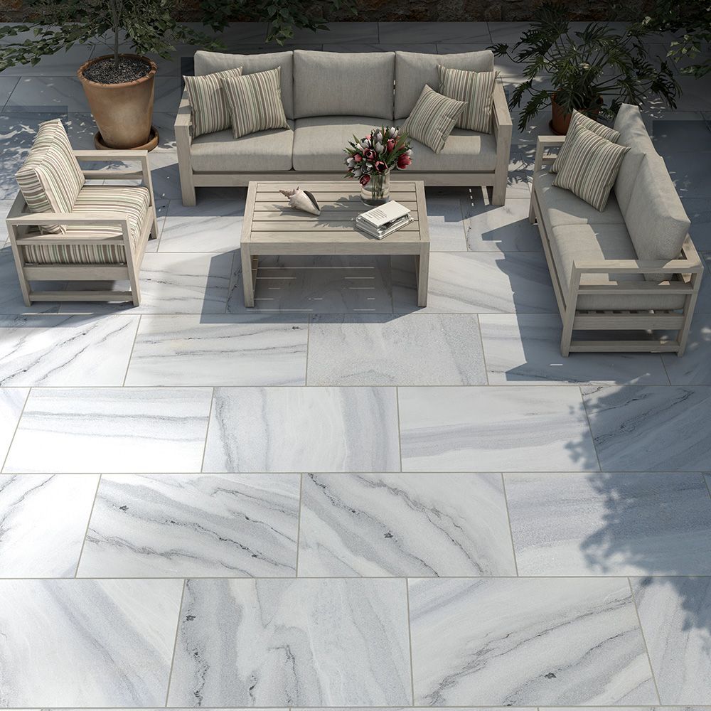 Patio furniture on a white marble patio, with plants and sunlight.