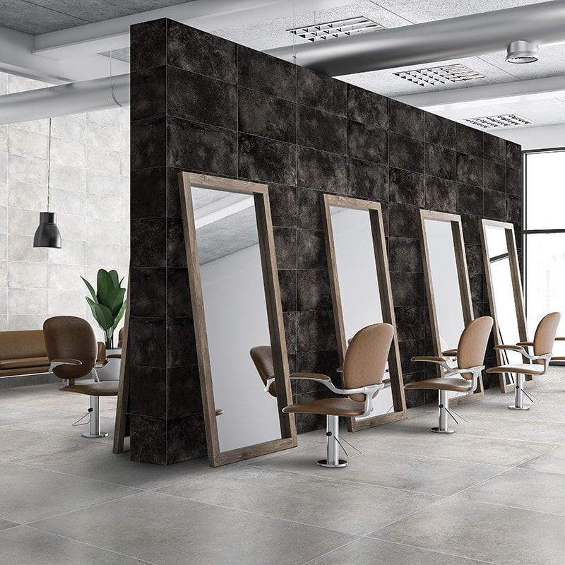 Hair salon interior with mirrors against a dark, textured wall and chairs.