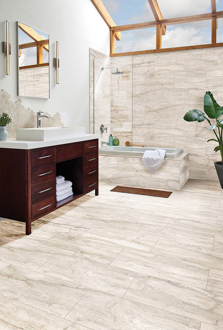 Bathroom with cream-colored stone tile, dark wood vanity, white sink, and a skylight.