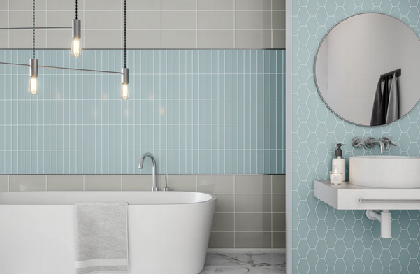 Bathroom with a white tub, blue tiled accent wall, and round mirror.