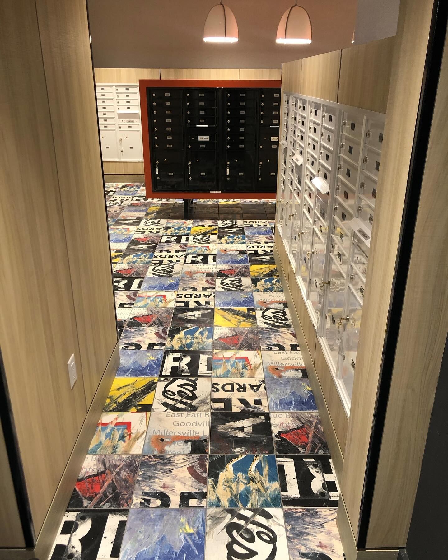 Hallway with colorful floor tiles leading to mailboxes.