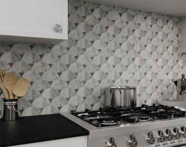 Kitchen with stove and backsplash featuring patterned, gray and white tiles.