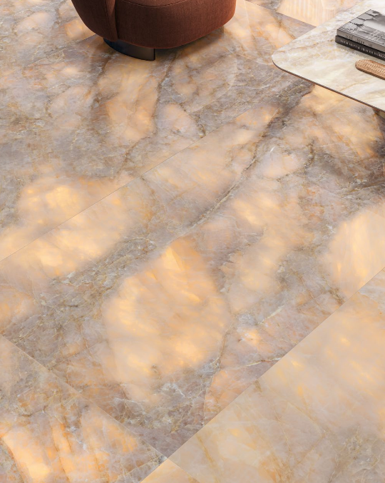 Floor with large marble tiles, tan and gray tones, with a warm, glowing appearance.