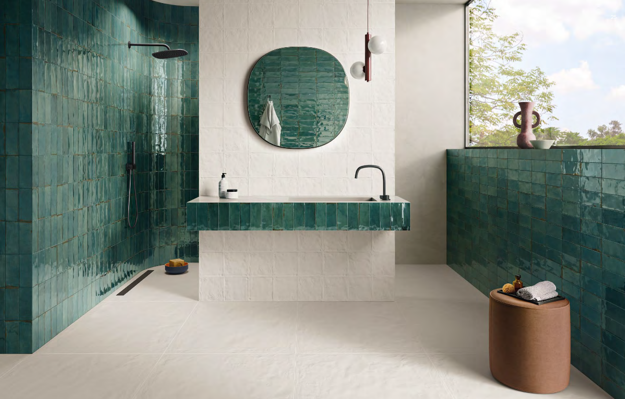 Green tiled bathroom with white walls, a large mirror, and natural light.