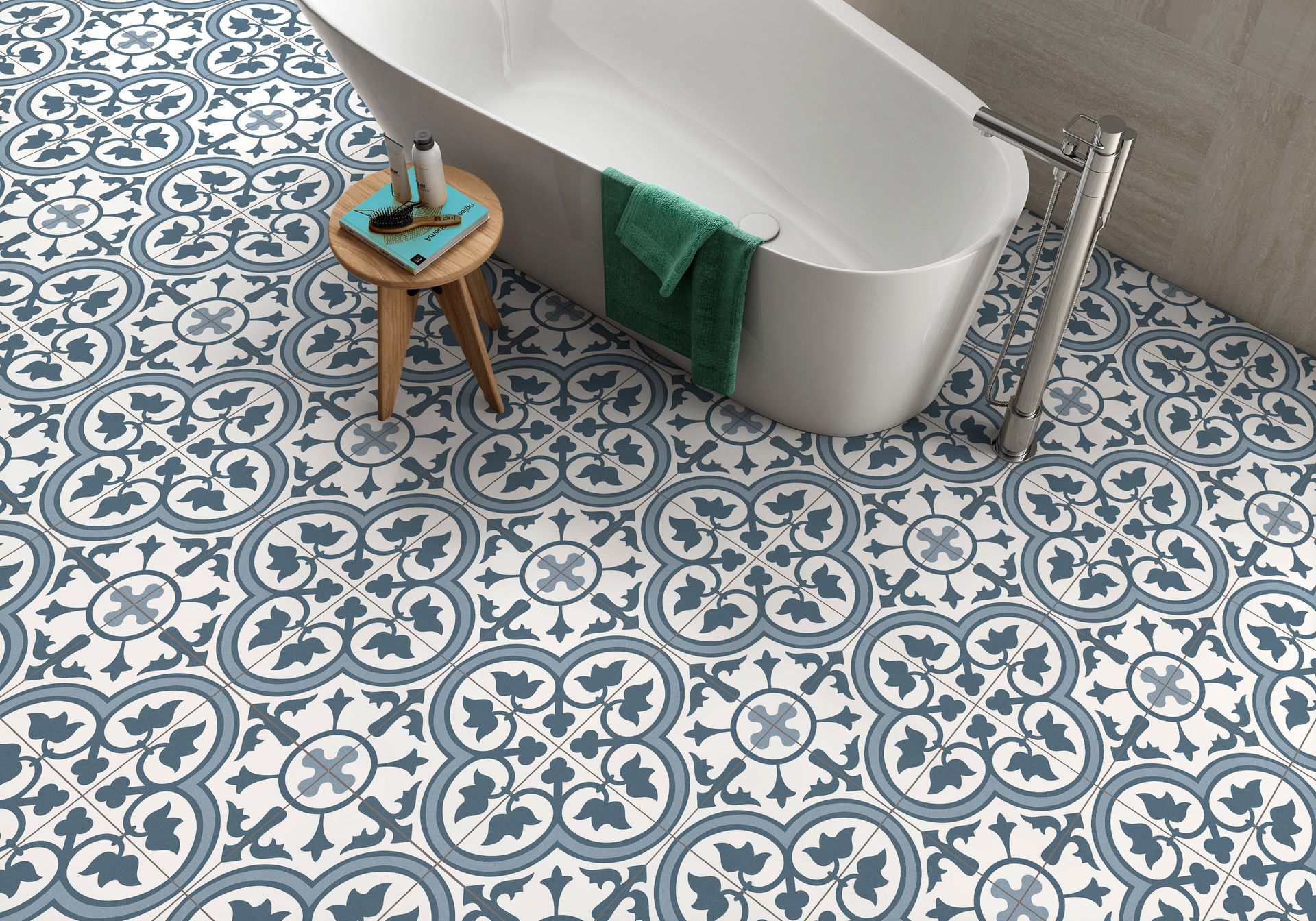 Blue and white patterned bathroom floor with a white soaking tub, a small stool, and a green towel.