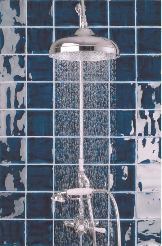 Chrome showerhead with running water against a blue and white tiled wall.