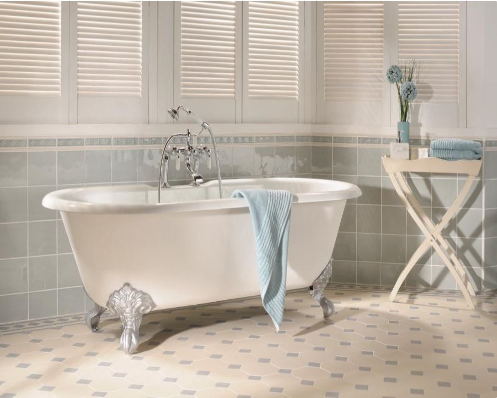 Clawfoot tub in a light blue-tiled bathroom with shuttered windows, towels, and flowers.