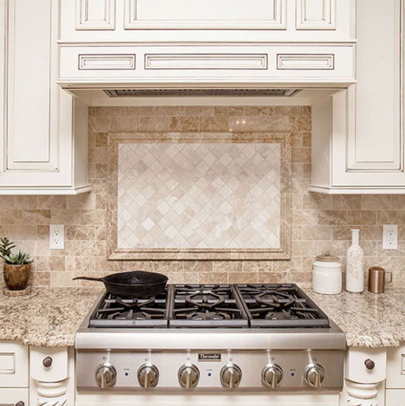 A kitchen stove with a decorative tile backsplash and range hood.