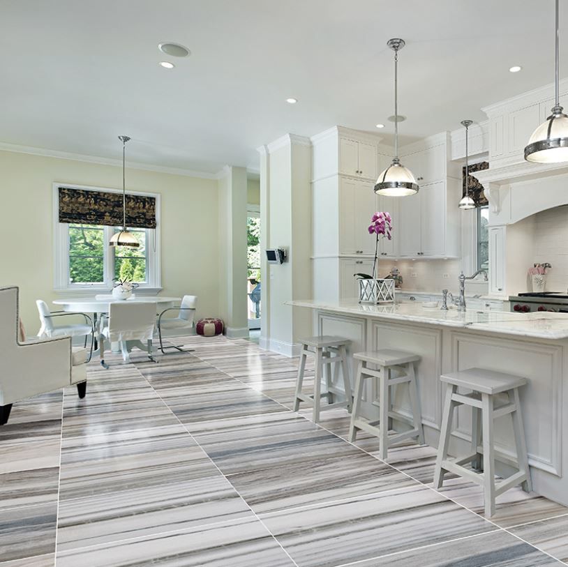 Kitchen with white cabinets, island, and striped gray and white tile floor.