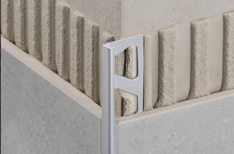 Corner tile edge with silver metal trim, showing a corner of a wall with tile.