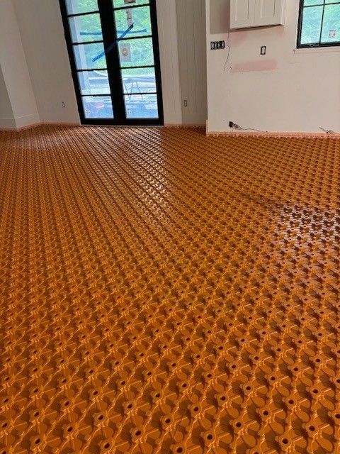 Orange radiant floor heating system installed in a room with a black framed door.