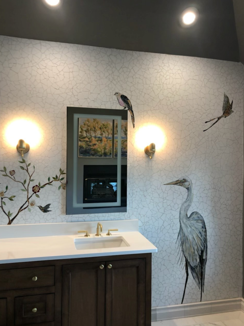 Bathroom with bird decals on textured wall, a mirror, and vanity with gold fixtures.