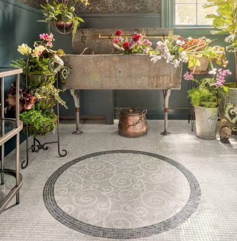 Bathroom with mosaic floor, weathered metal sink overflowing with flowers and plants.