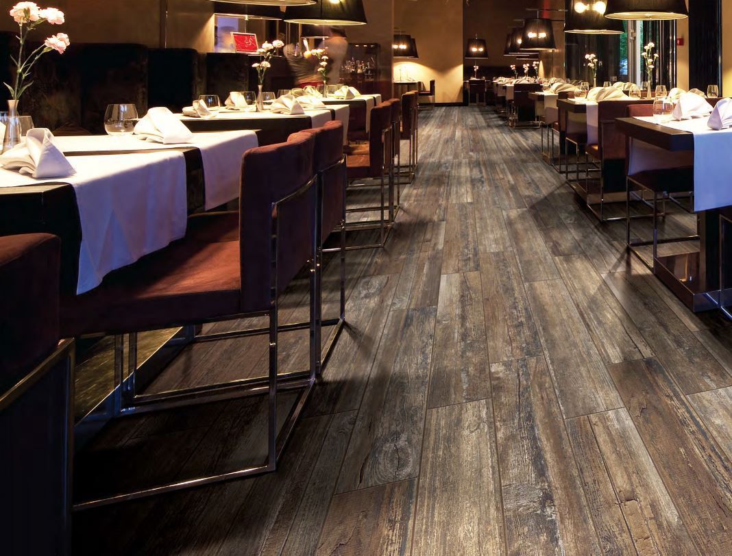 Restaurant interior with dark wood flooring and tables set with white tablecloths.