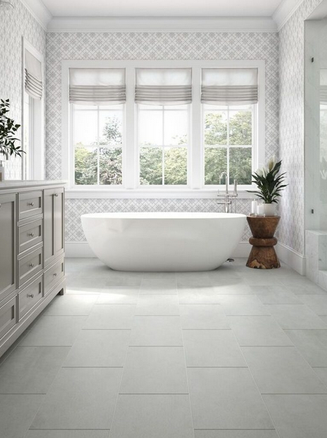 White bathroom with bathtub, windows, and vanity. Gray tile floor.