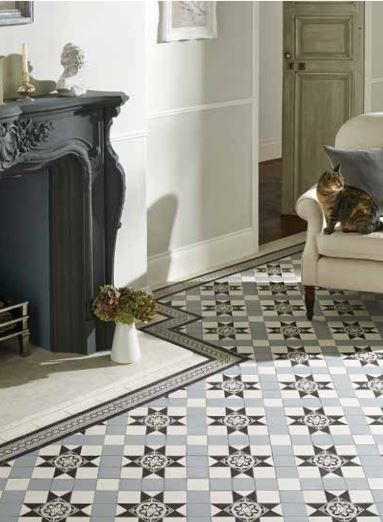 Decorative floor tiles in a room with a fireplace, a cat on a chair, and a vase of flowers.