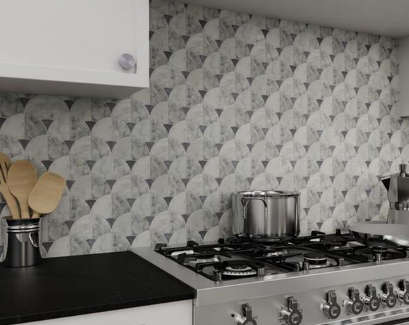 Kitchen with patterned backsplash, black countertop, stove, pot, and wooden utensils.