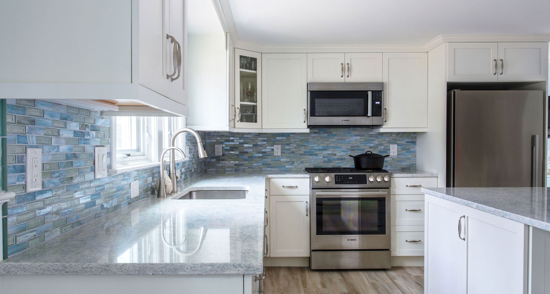 White kitchen with blue tile backsplash, stainless steel appliances, and granite countertops.