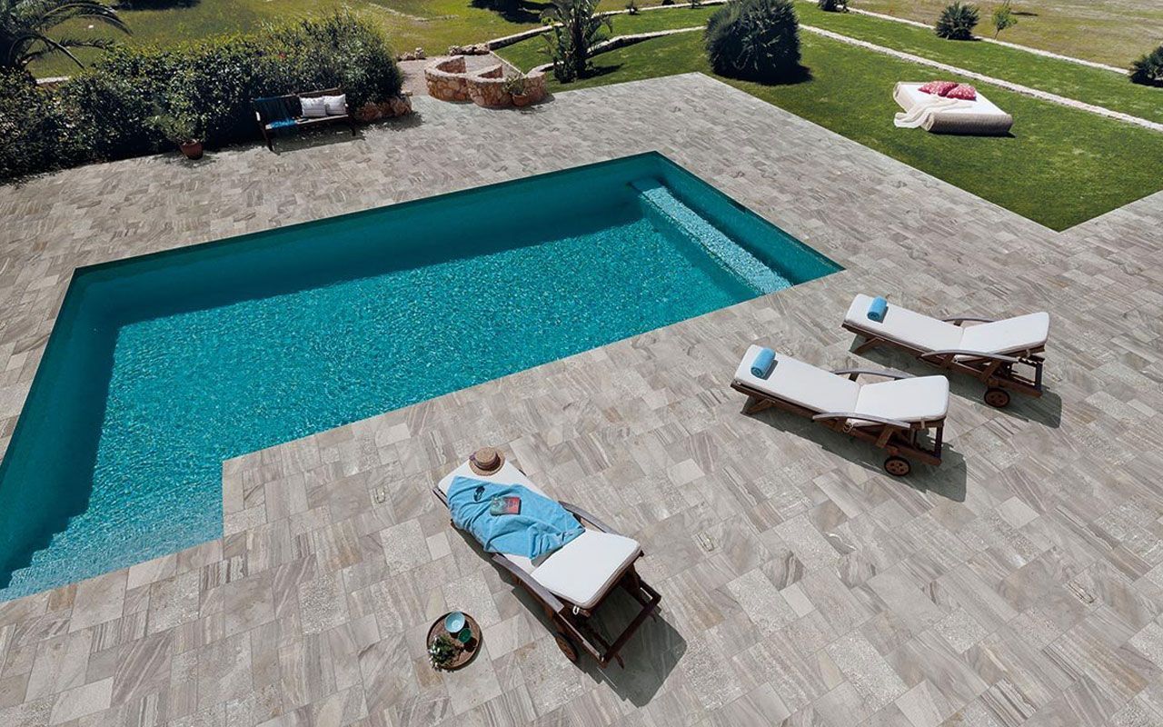 Pool with blue water, lounge chairs, and lawn in a sunny outdoor setting.