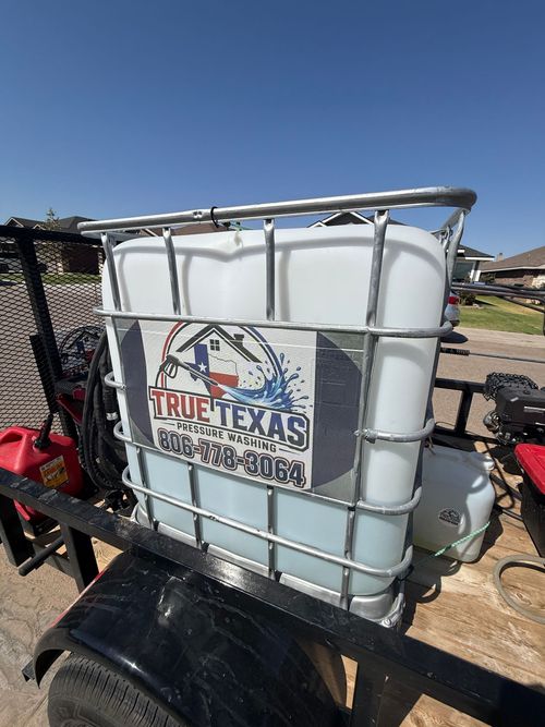 White water tank in metal cage on a trailer, labeled True Texas, outdoors under a blue sky