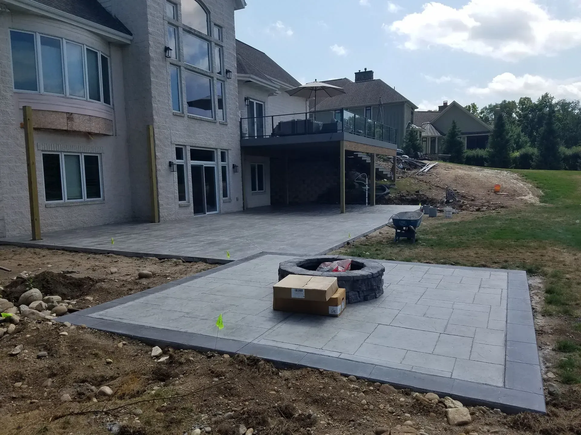 A fire pit is sitting in the middle of a patio in front of a large house.