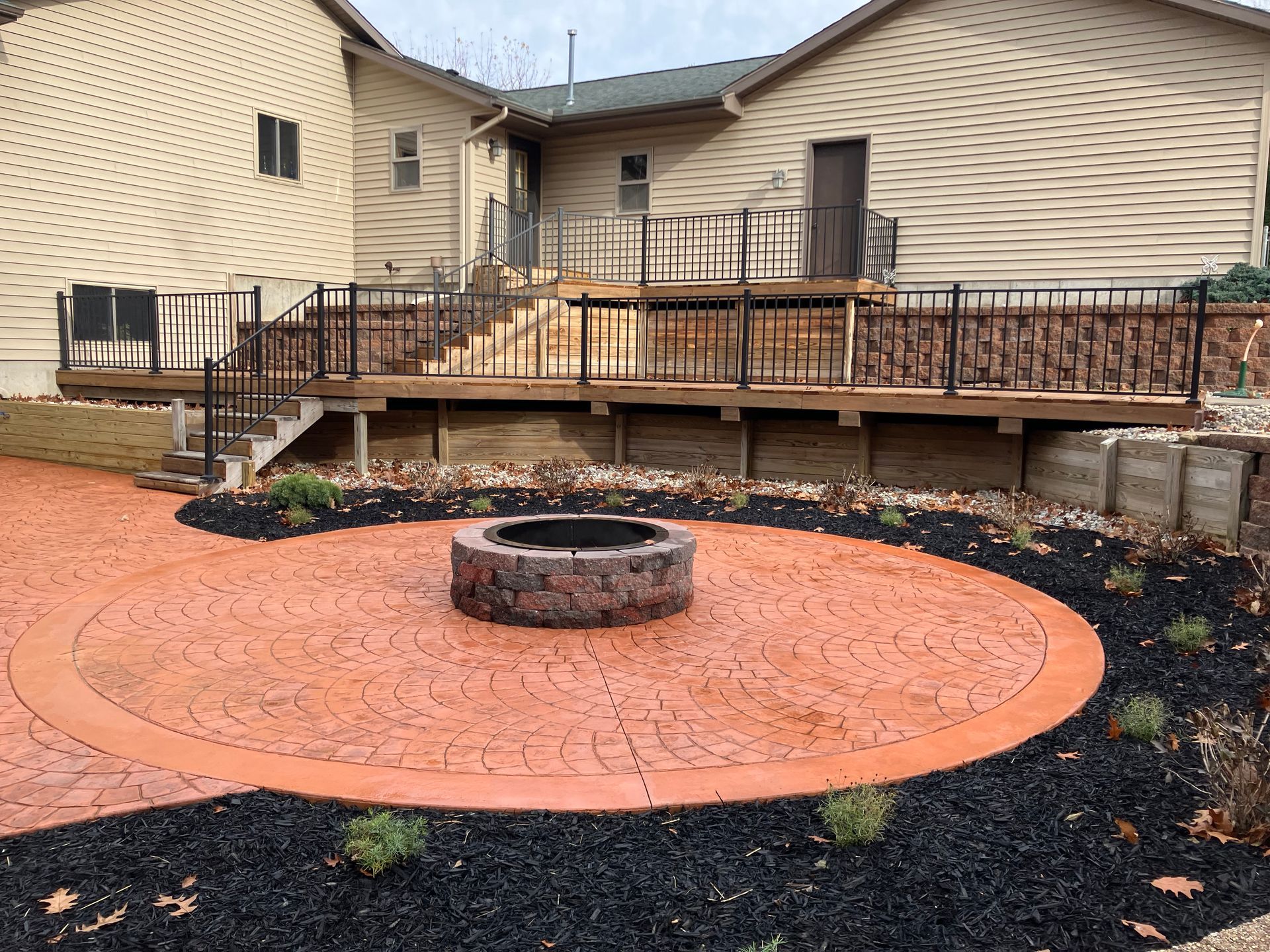 A fire pit sits at the center of a stamped concrete patio.
