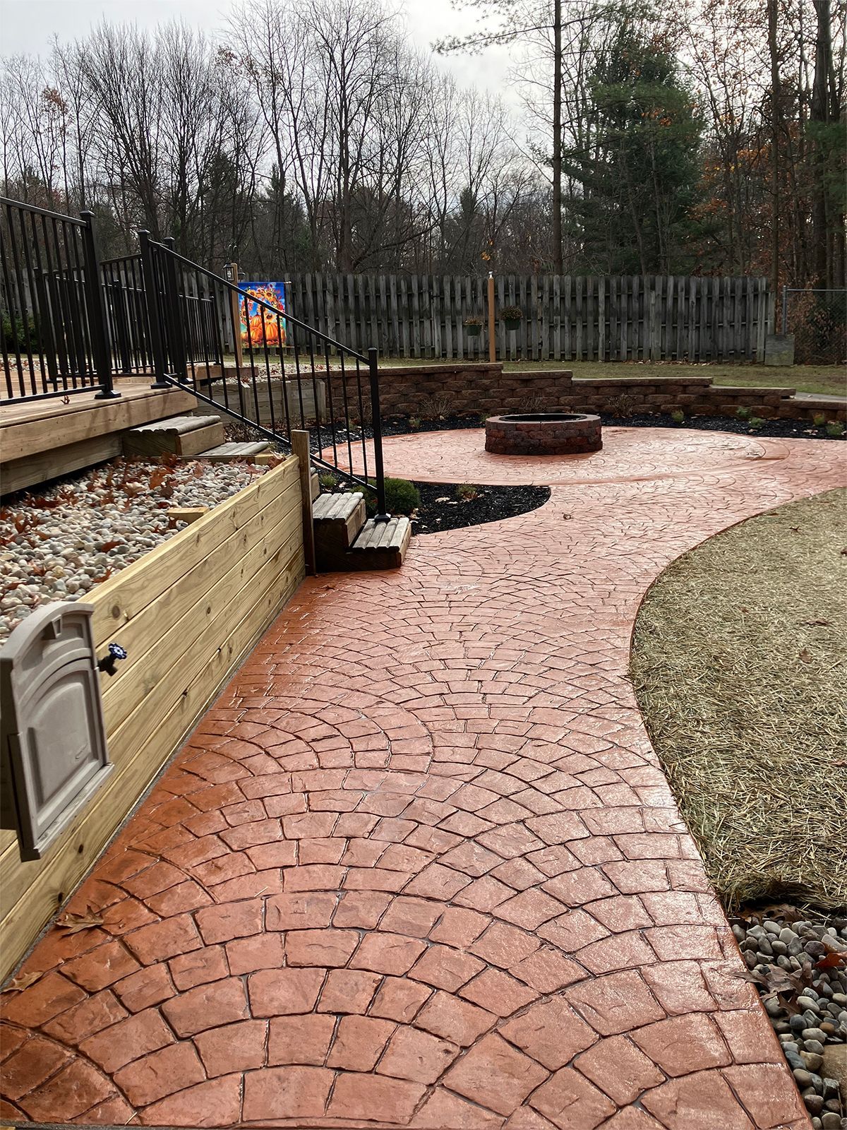 A stamped concrete walkway leads to a fire pit in the backyard.