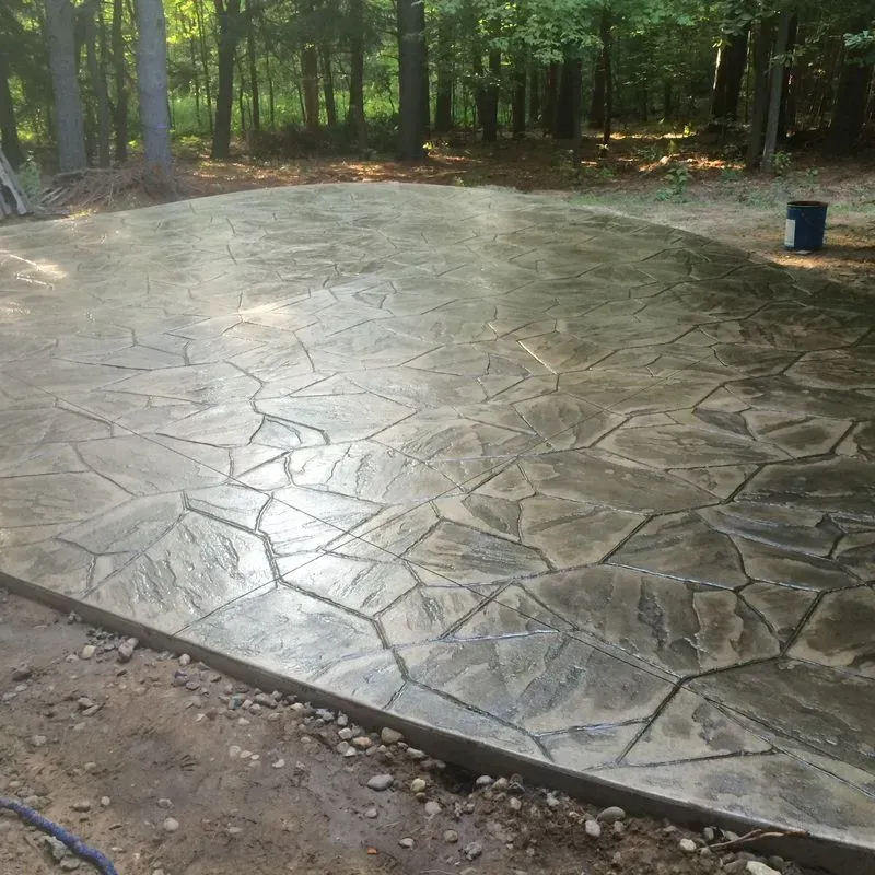 A concrete patio in the middle of a forest with trees in the background.
