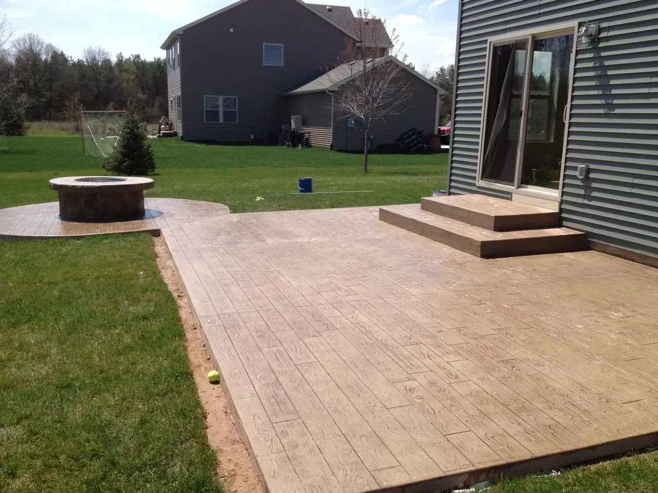 A patio with stairs and a fire pit in the backyard of a house.