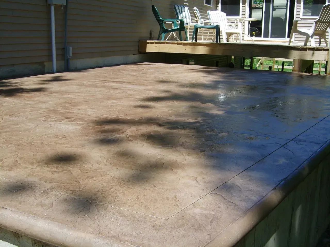 A concrete deck with chairs and a house in the background