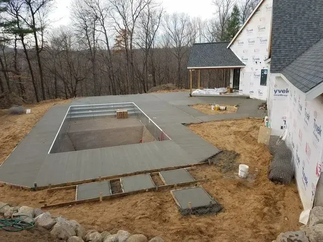 A swimming pool is being built in the backyard of a house.