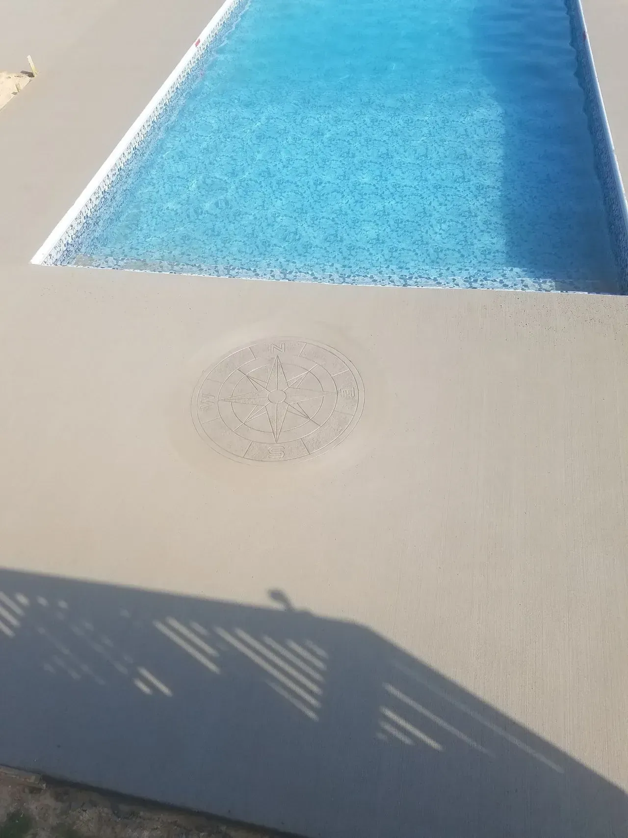 There is a hole in the ground next to a swimming pool.