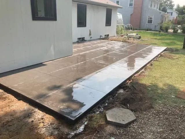 A concrete patio is being built in front of a house.